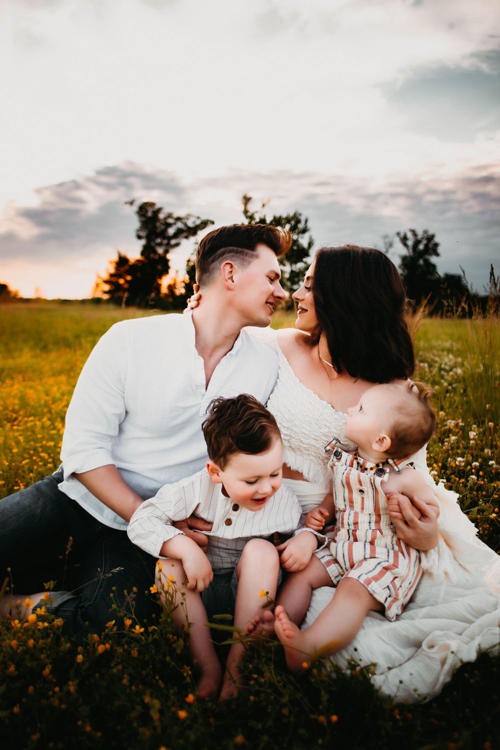 Sweet family interactions during an outdoor photo session among wildflowers at dusk.