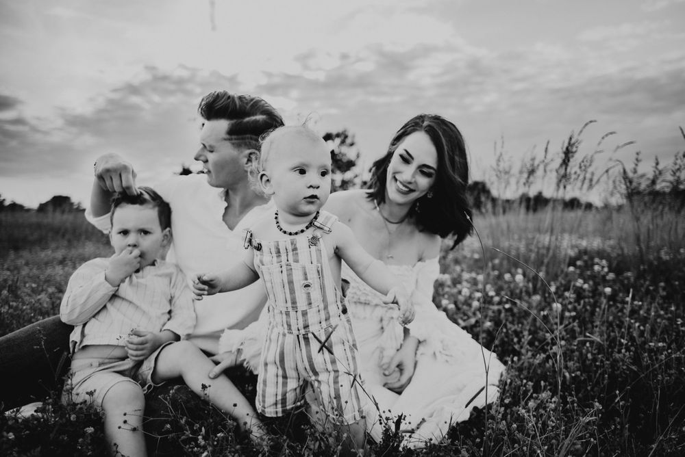 Black and white family portrait session in a natural outdoor setting with tall grass.