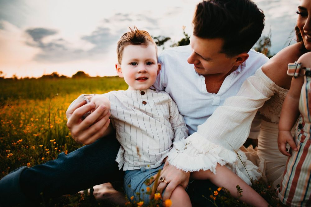 Relaxed family lifestyle session among blooming wildflowers at sunset.