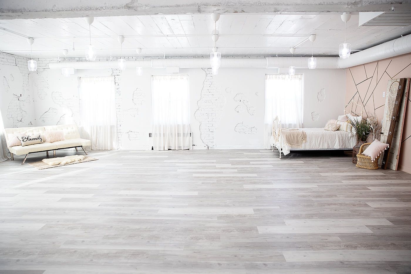Bright white studio space with cream colored furniture and hardwood floors.