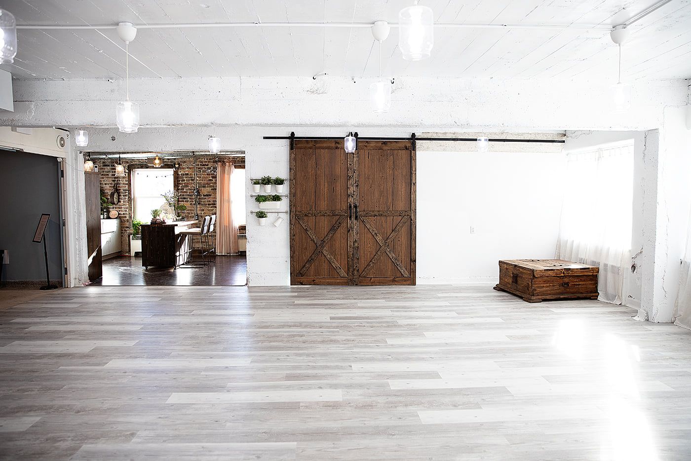 Industrial style room with sliding barn doors, white walls, and wood flooring.