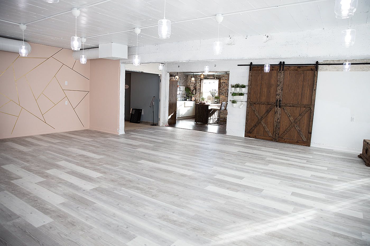 Modern open concept room with gray wood flooring and a sliding barn door featuring geometric wall designs.