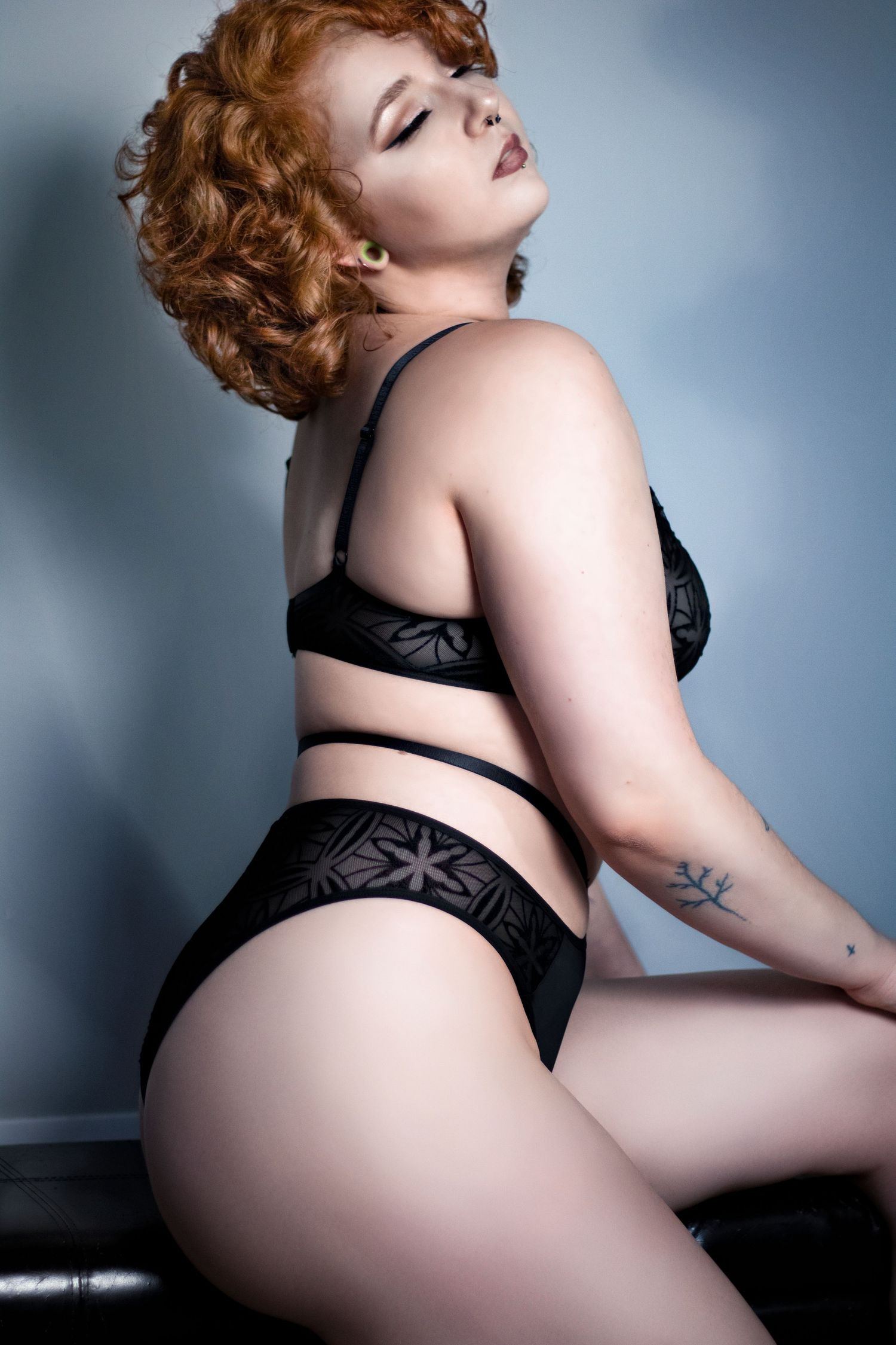 Artistic boudoir photo featuring black lingerie against a blue-grey backdrop.