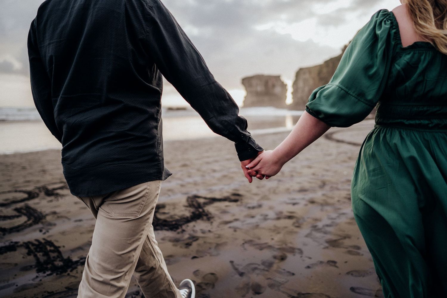 A couple holding hands on a beach at sunset