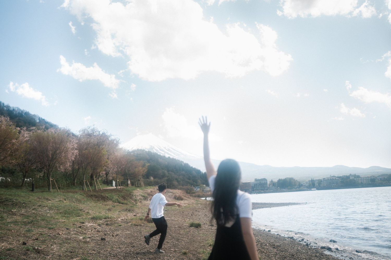 Playful scene by a lake with mountains and blue sky in the background.