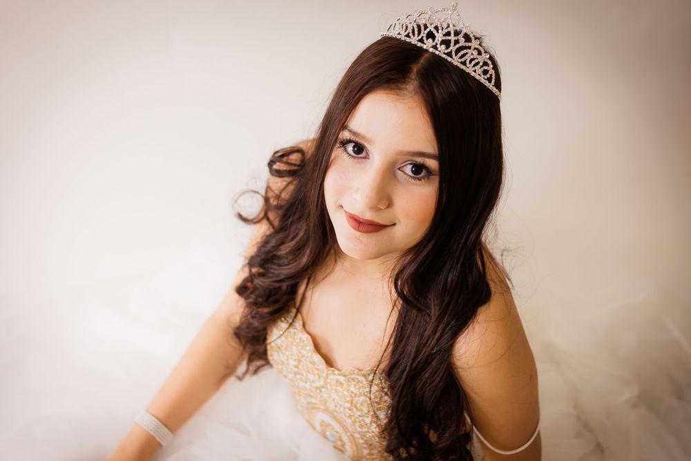 An elegant portrait featuring a sparkly tiara and embellished dress in soft lighting.