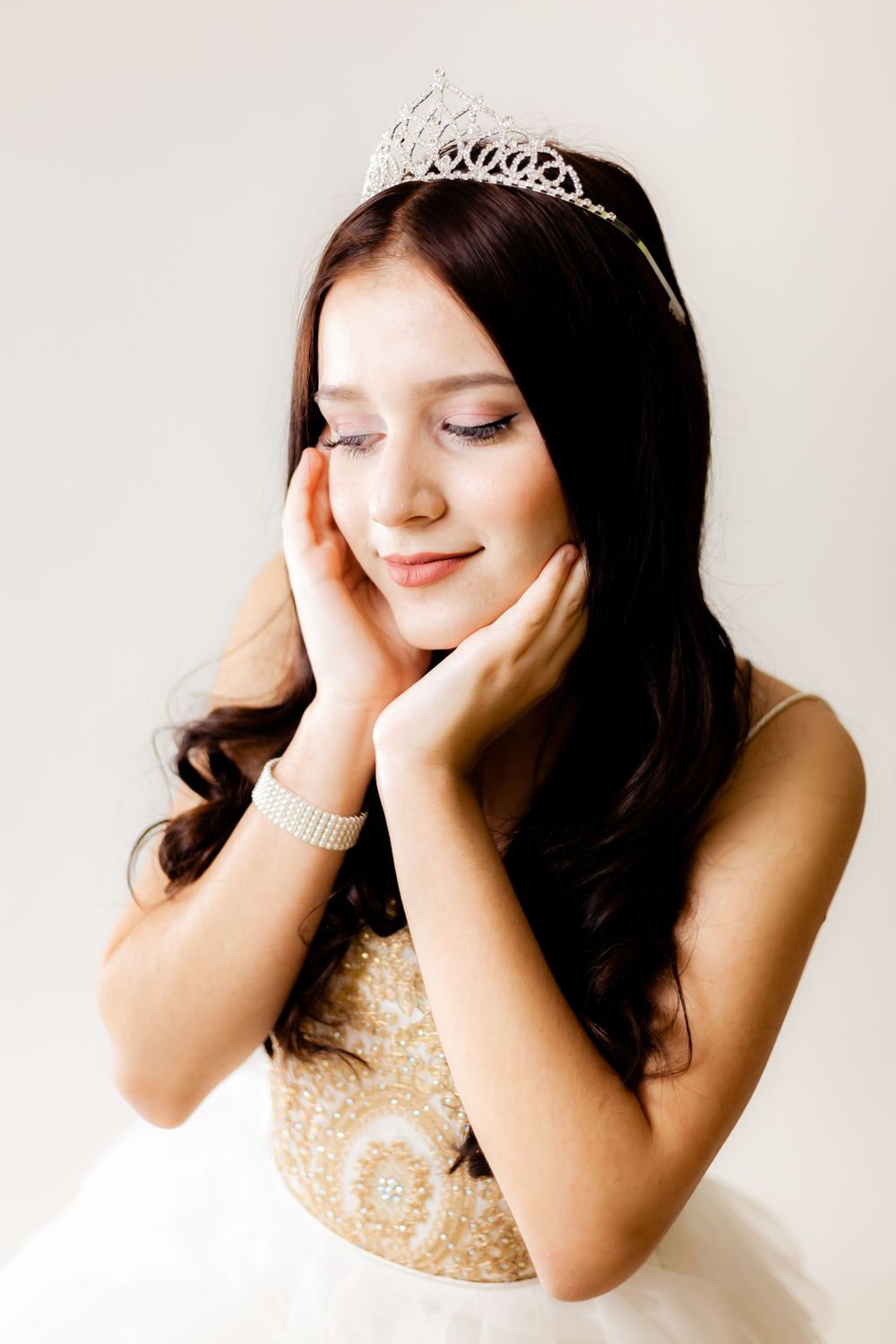 Dreamy portrait of young woman in formal attire with eyes closed and tiara.