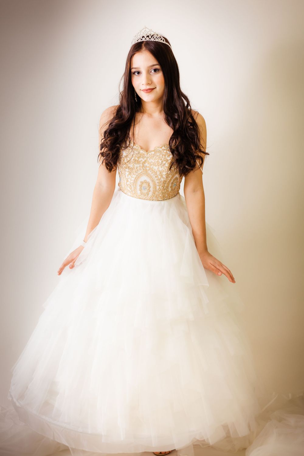 Full-length portrait showcases princess-style ball gown with gold details and crystal crown.