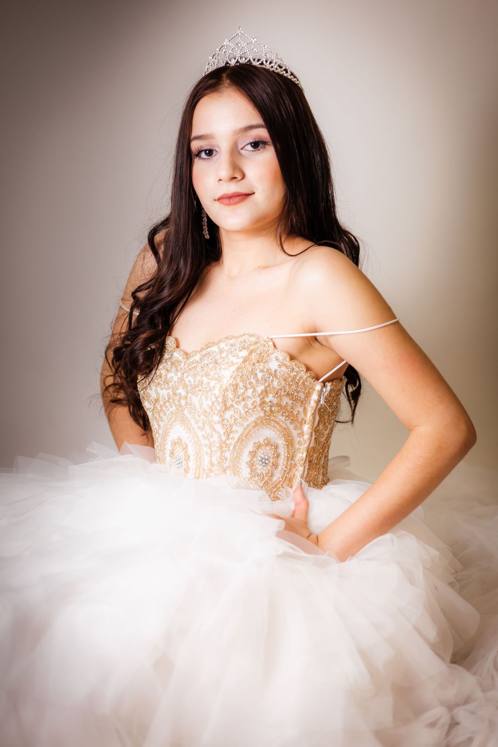 Glamorous pose in a white ballgown featuring detailed beadwork and crystal crown.