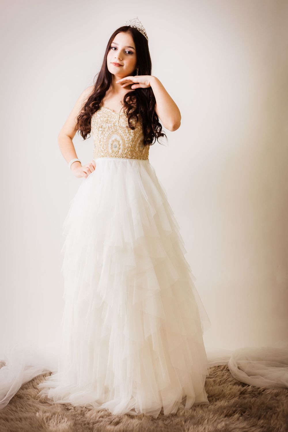 Graceful pose in a strapless white ball gown with gold beaded top and flowing skirt.
