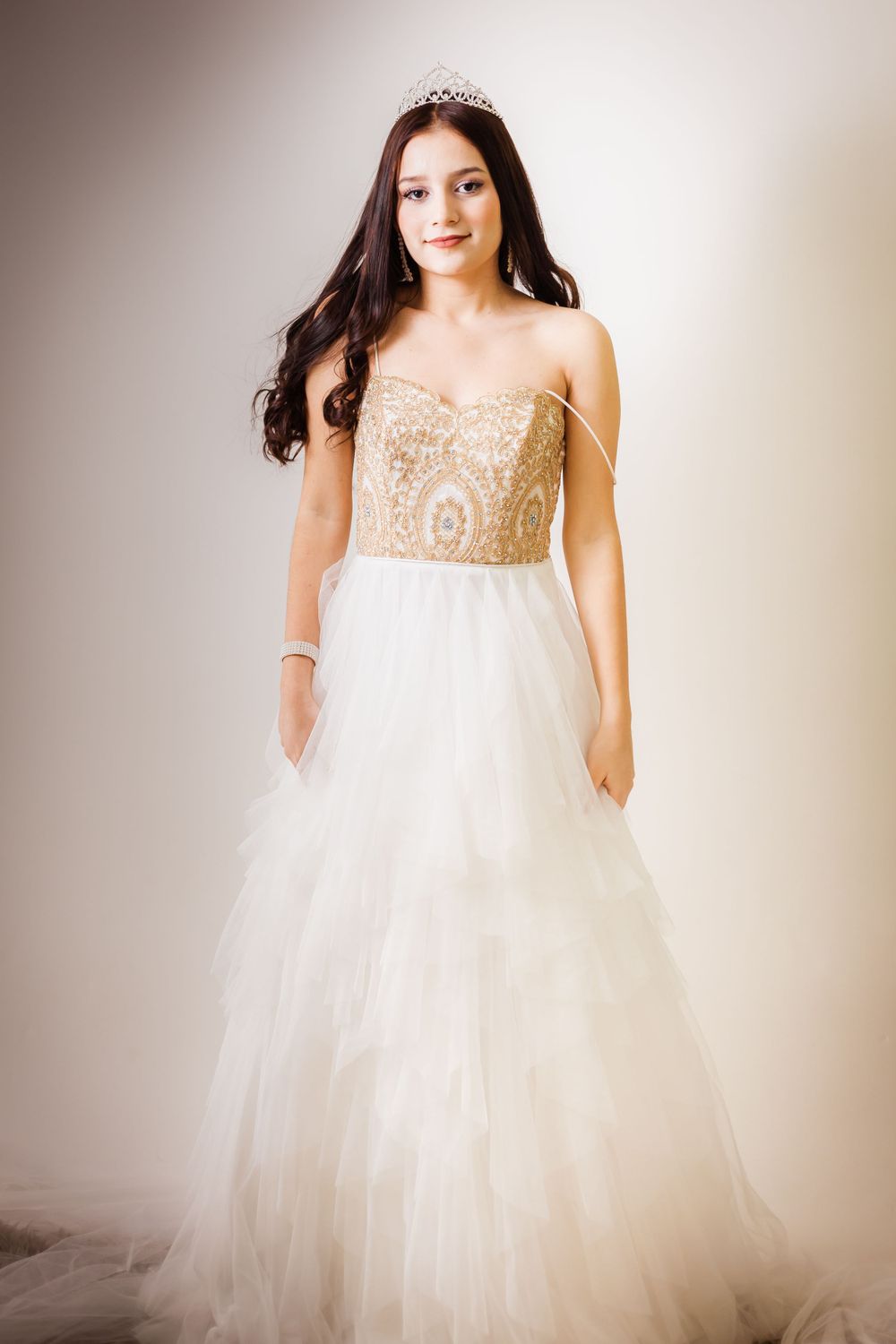 Full-length view of princess wedding dress with gold embellished bodice and tiara.