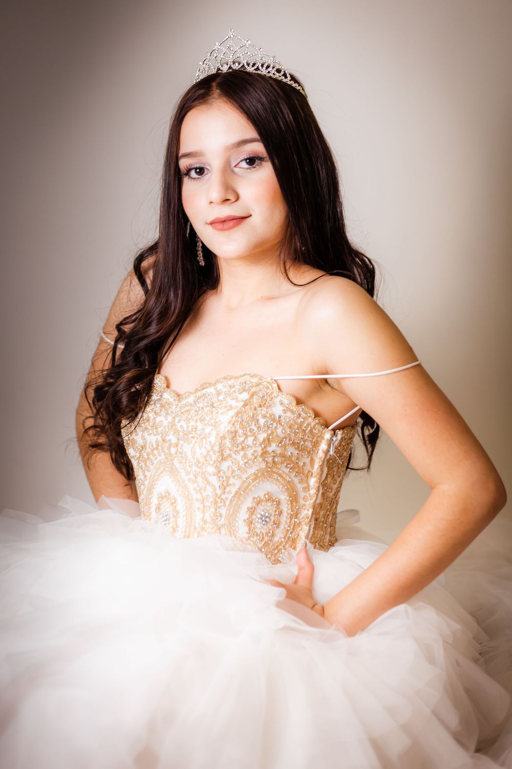 Beautiful quinceañera dress featuring a gold embellished bodice and white tulle skirt with delicate tiara crown.