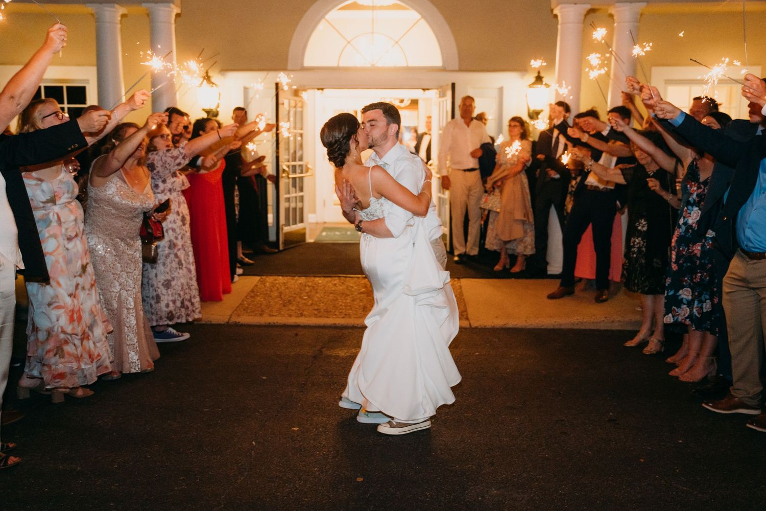 Wedding reception guests form a dance line in an elegantly lit indoor space.