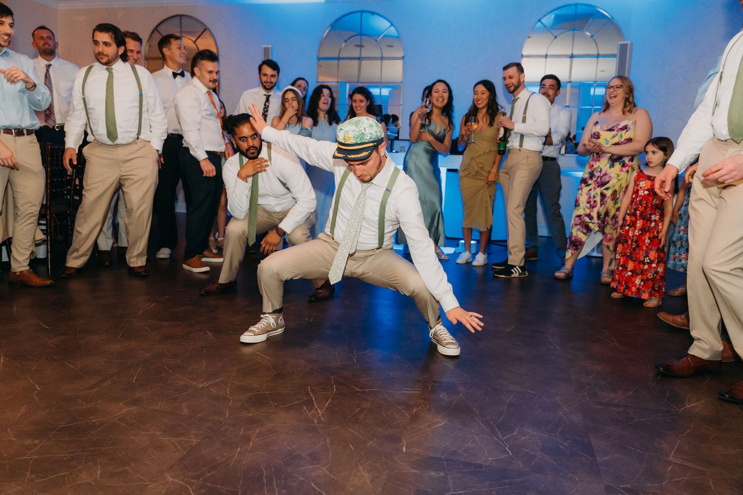 Large group of wedding guests dancing and celebrating on a wooden dance floor.