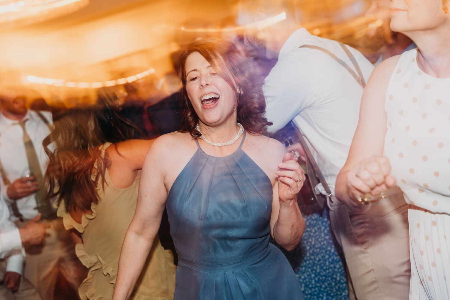 Guests enjoying themselves on a crowded dance floor with colorful lighting.