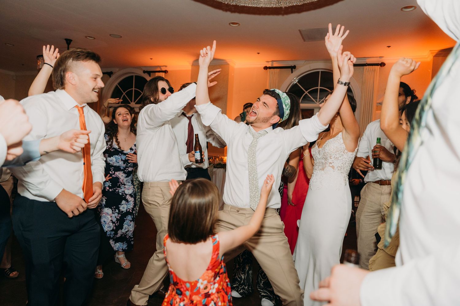 Energetic dancing and celebration at a wedding reception with guests raising their arms.