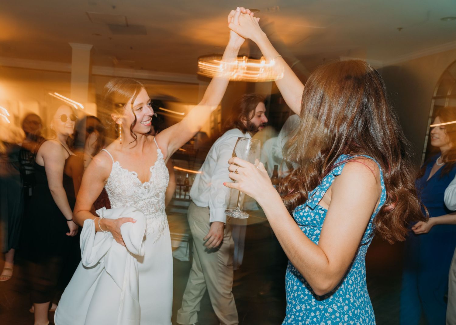 Guests dancing and having fun at a wedding reception with warm lighting.