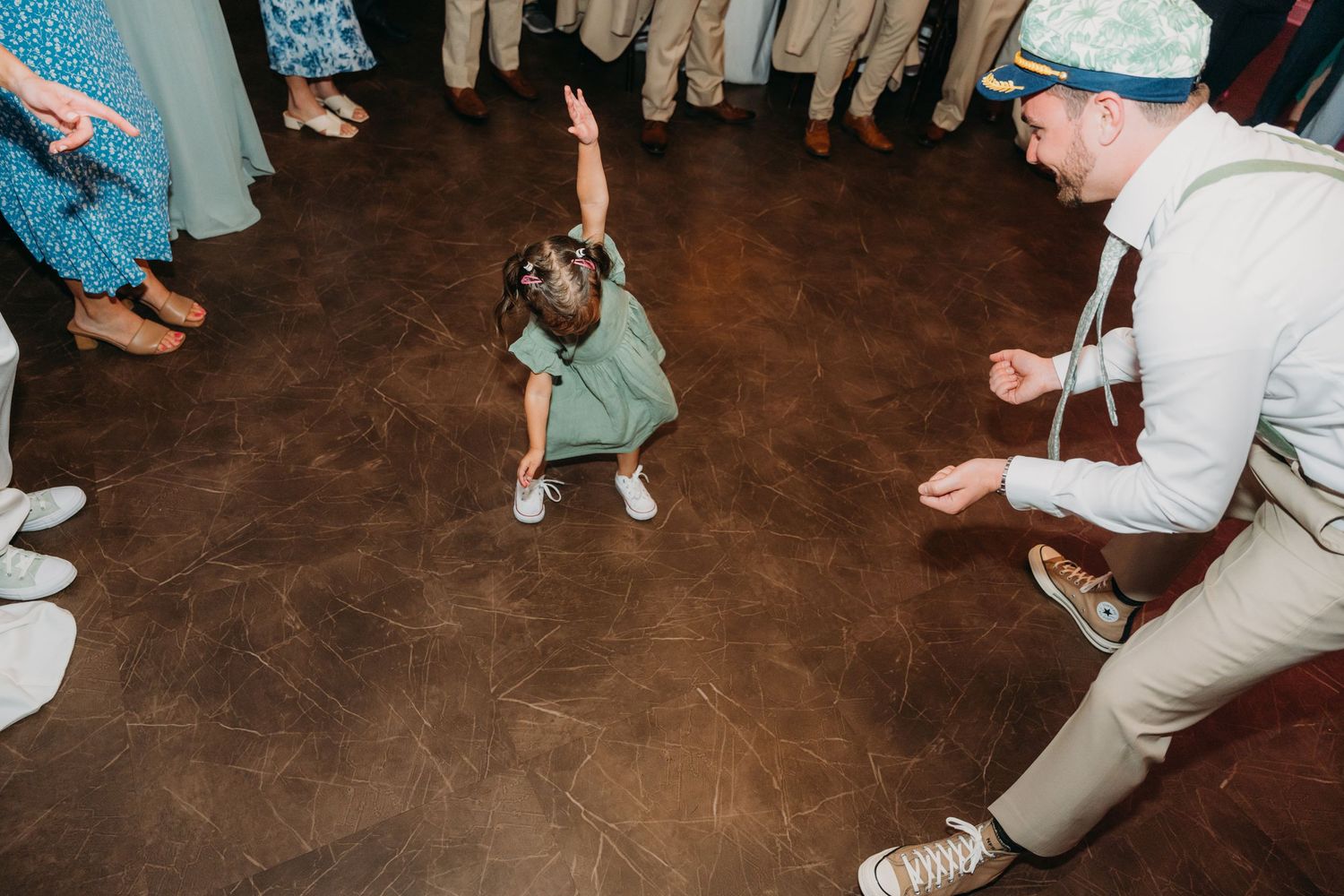 Wedding guests dancing and celebrating on a rustic wooden floor.