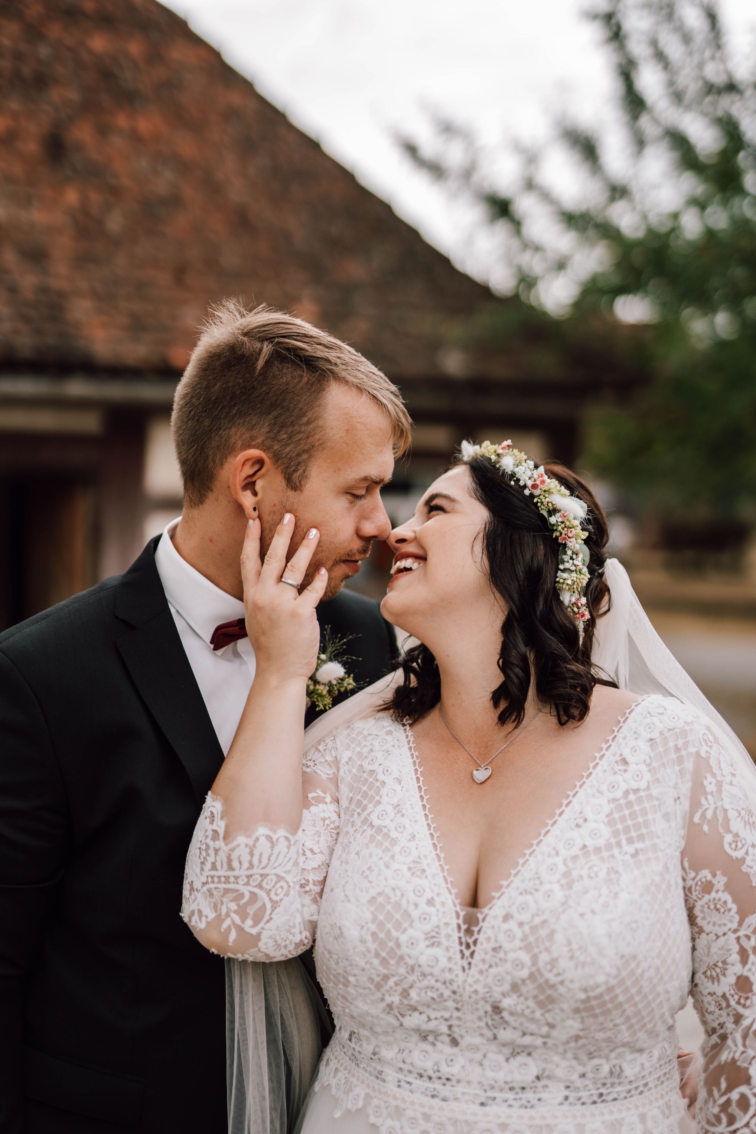Romantic wedding couple shares an intimate moment in front of a rustic brick building.