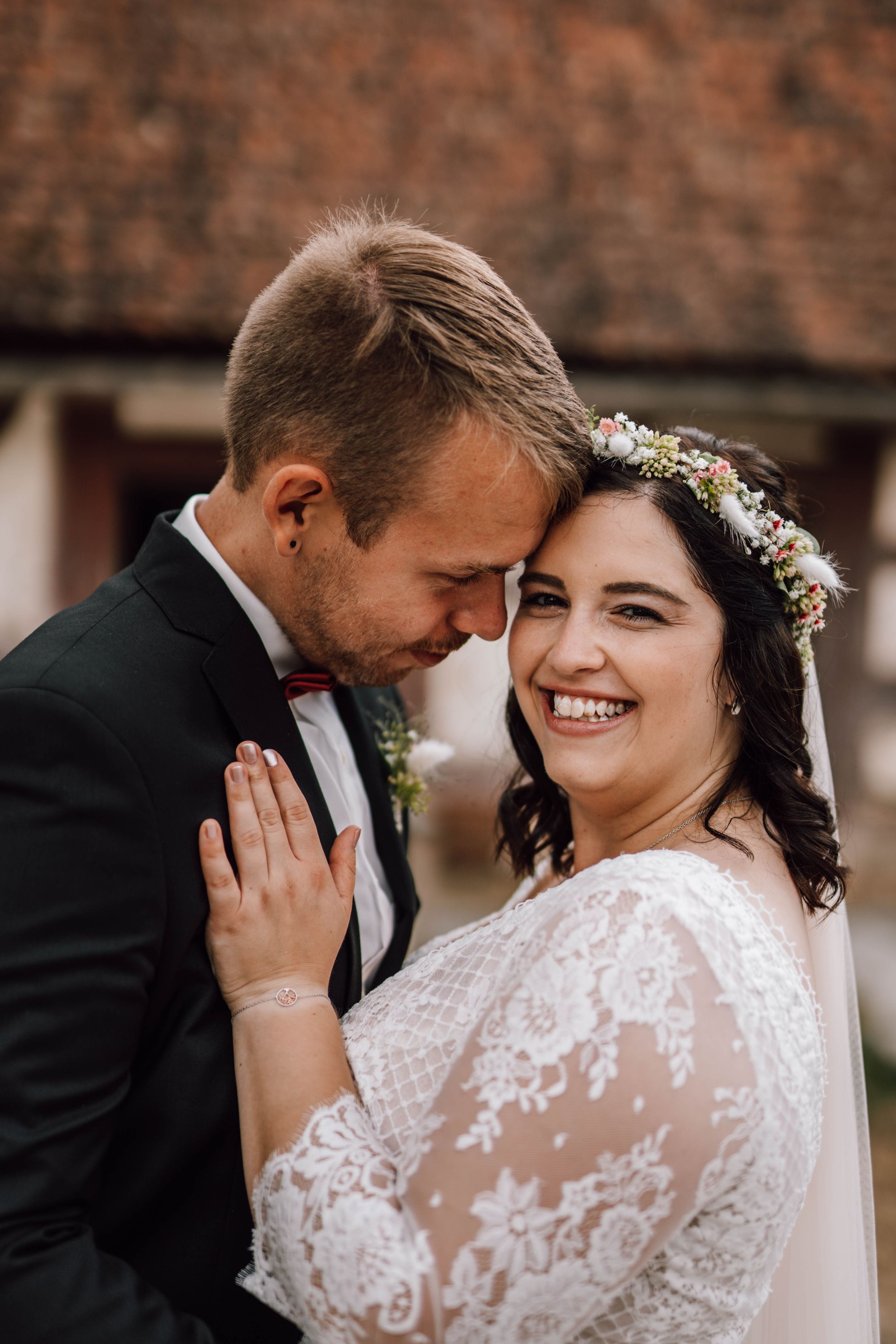 Intimate wedding portrait against rustic brick wall background.