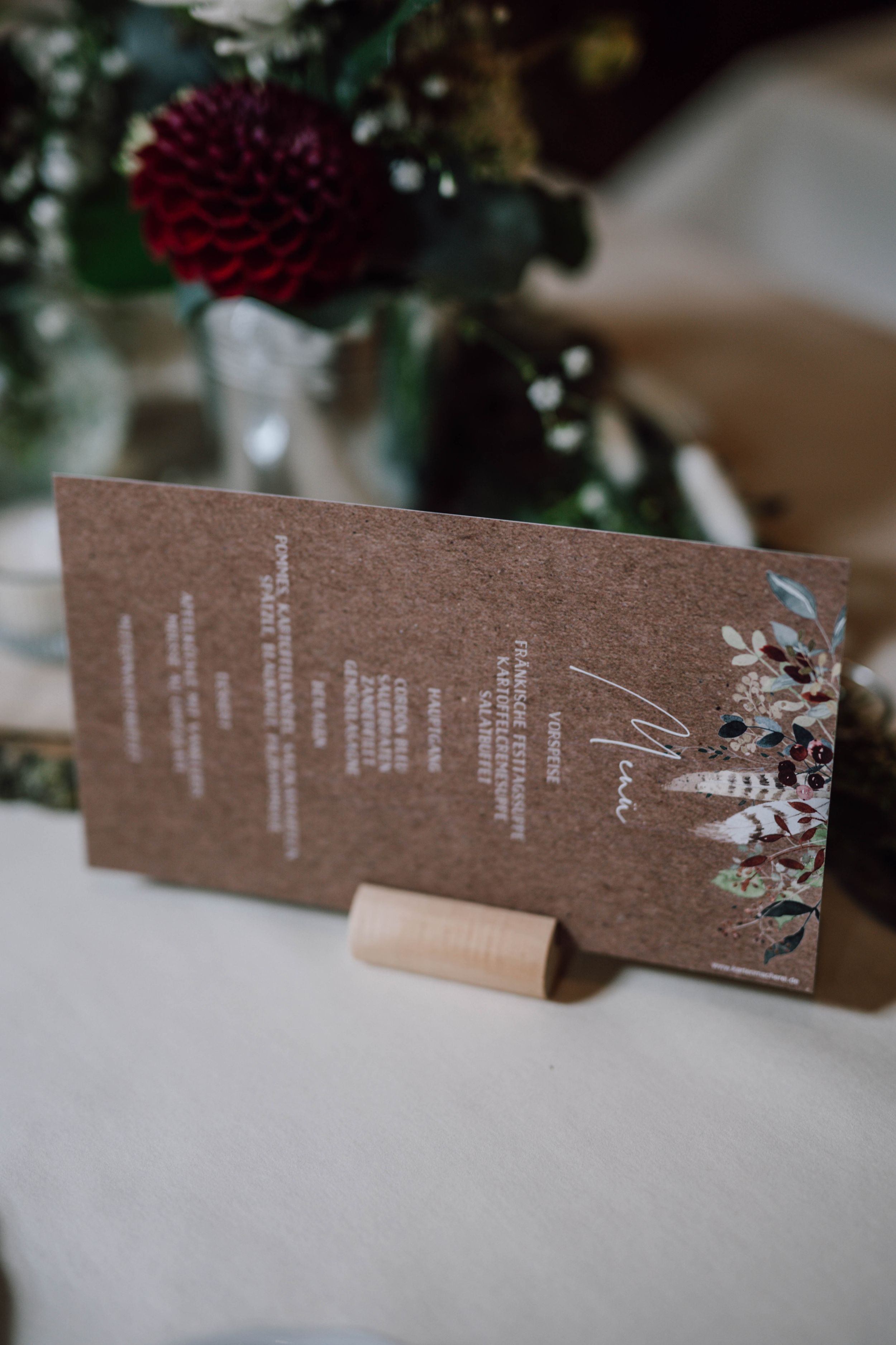 Brown kraft paper menu card with floral design displayed at wedding table setting.