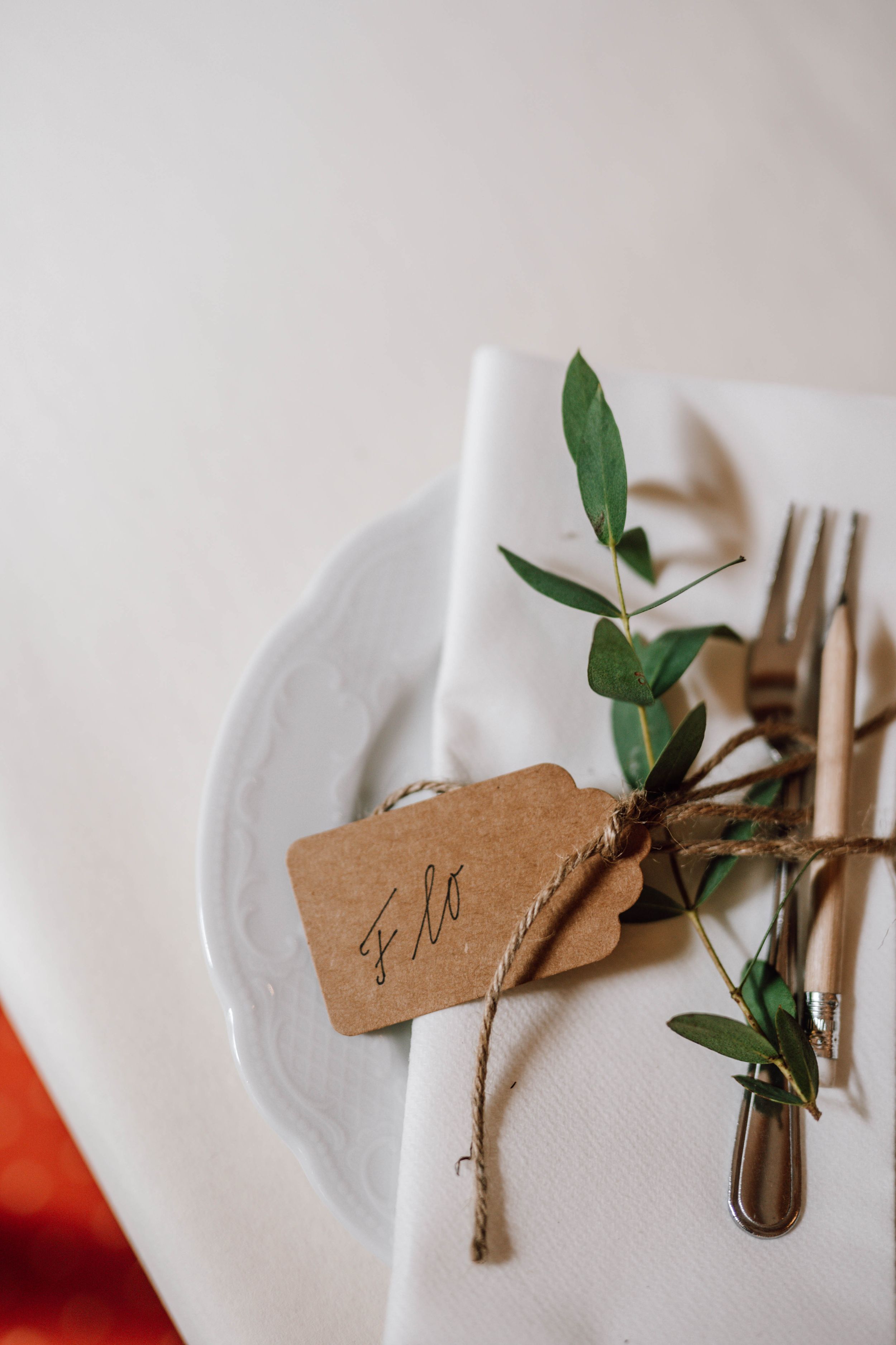 Elegant table setting with kraft paper name tag and greenery tied with twine.