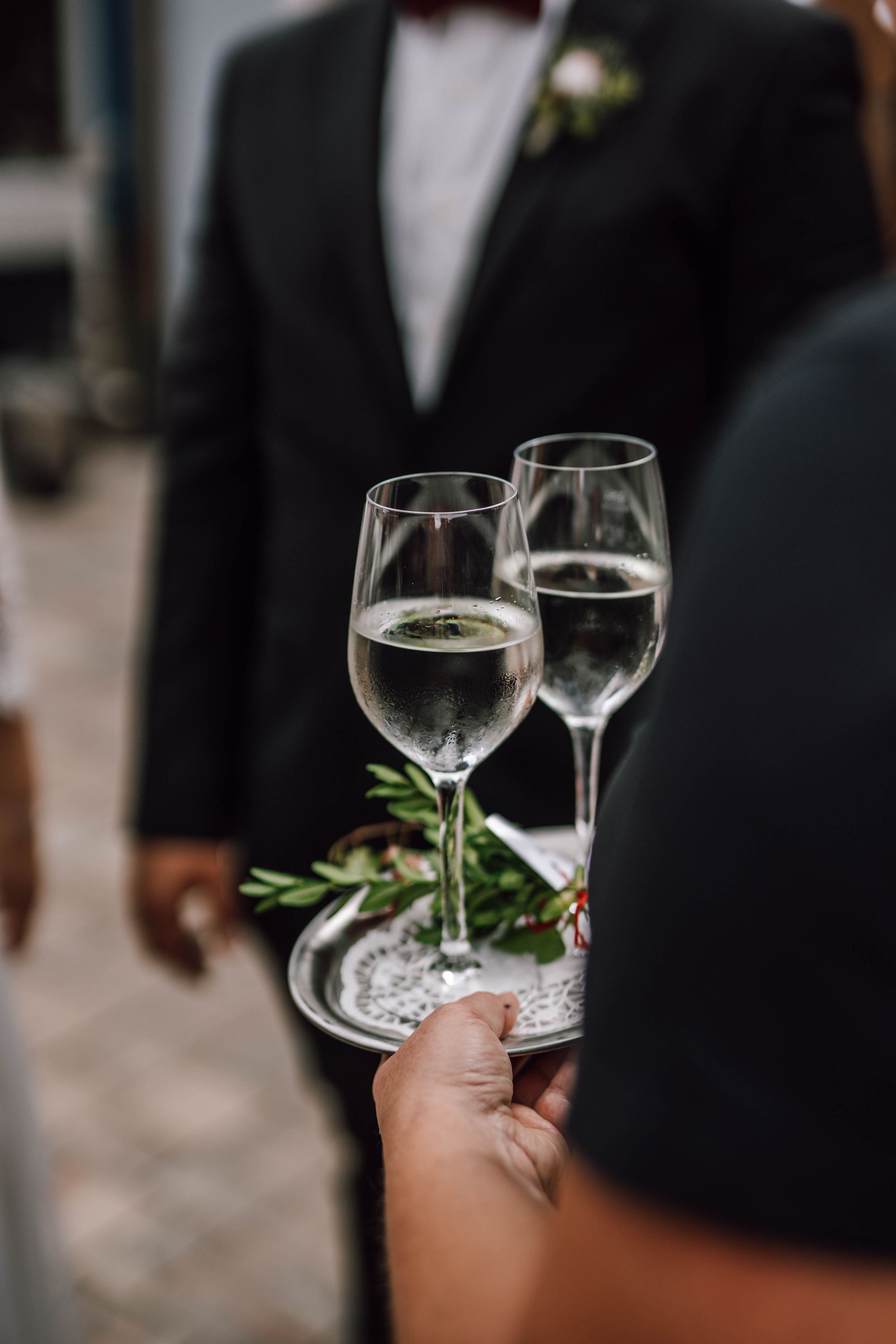 Two wine glasses being served on silver tray at formal event.
