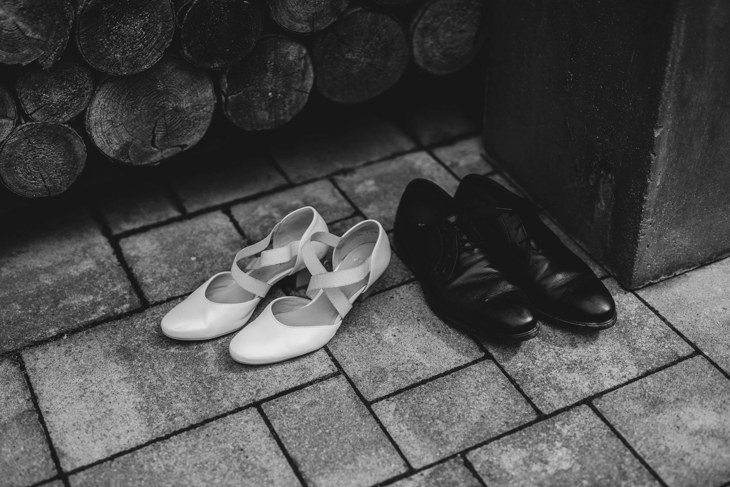 Black and white formal shoes placed side by side on stone pavement.