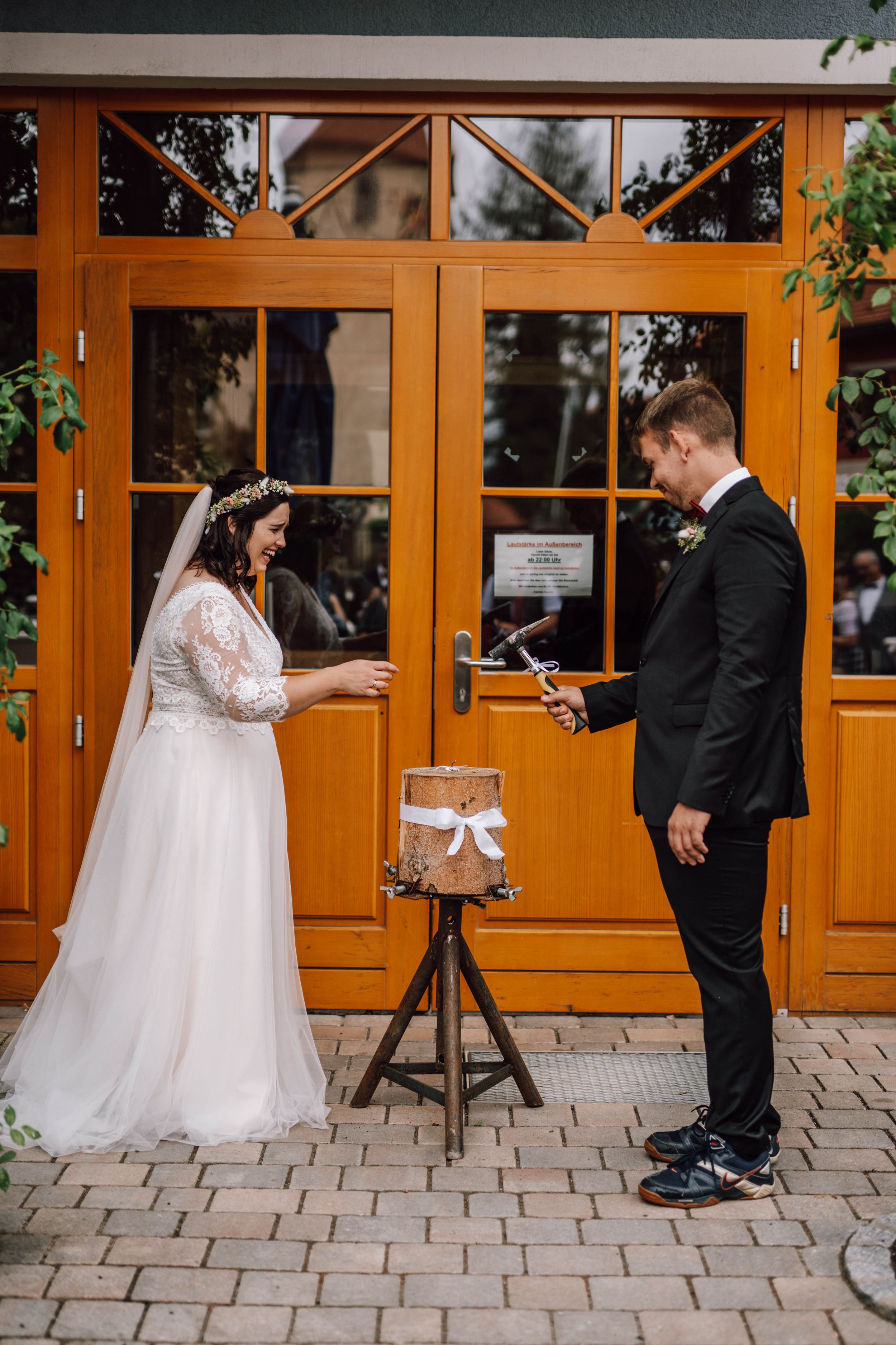 Wedding couple playfully poses in front of orange wooden doors on their special day.