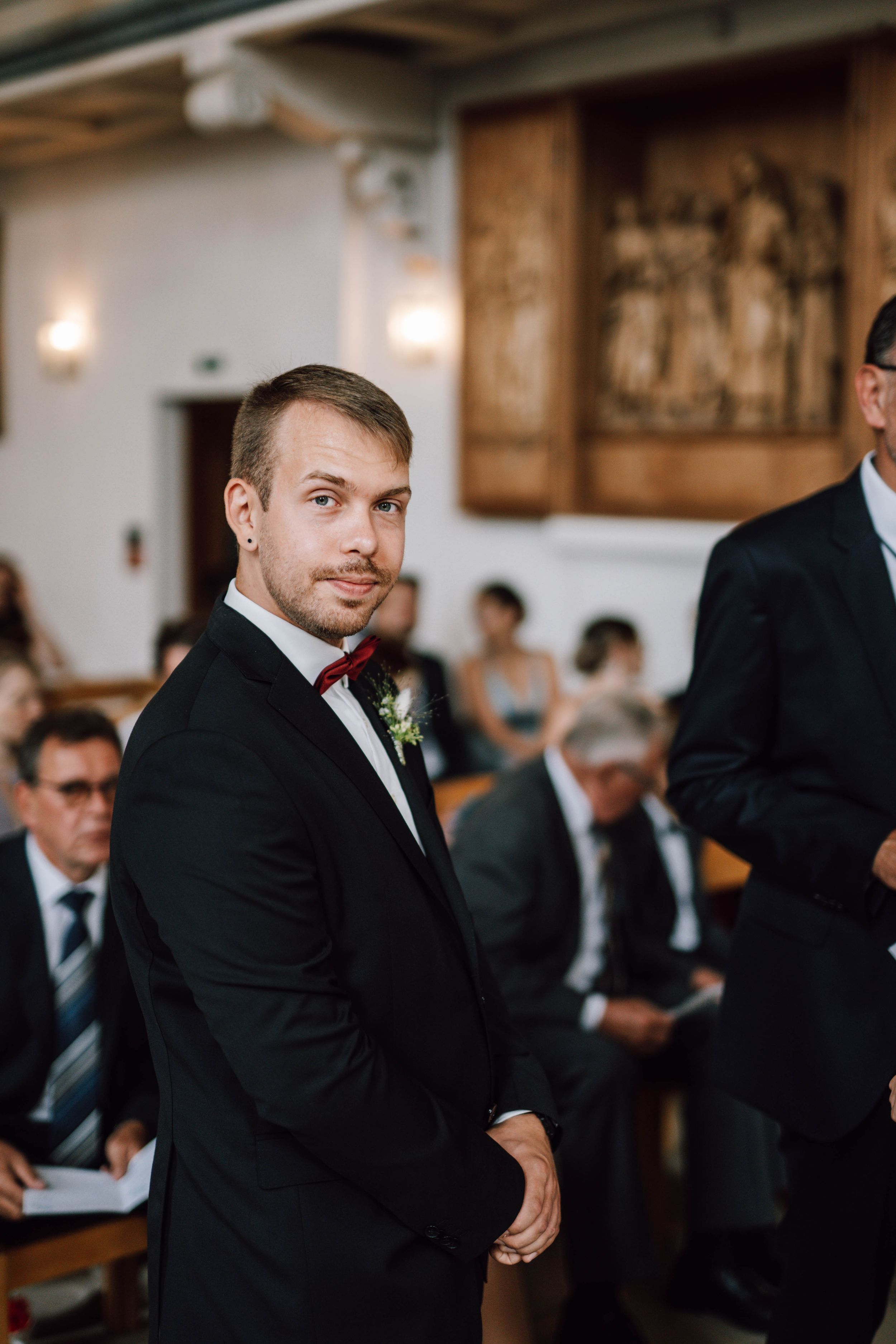 Wedding guests gather in an elegant indoor venue with warm lighting.