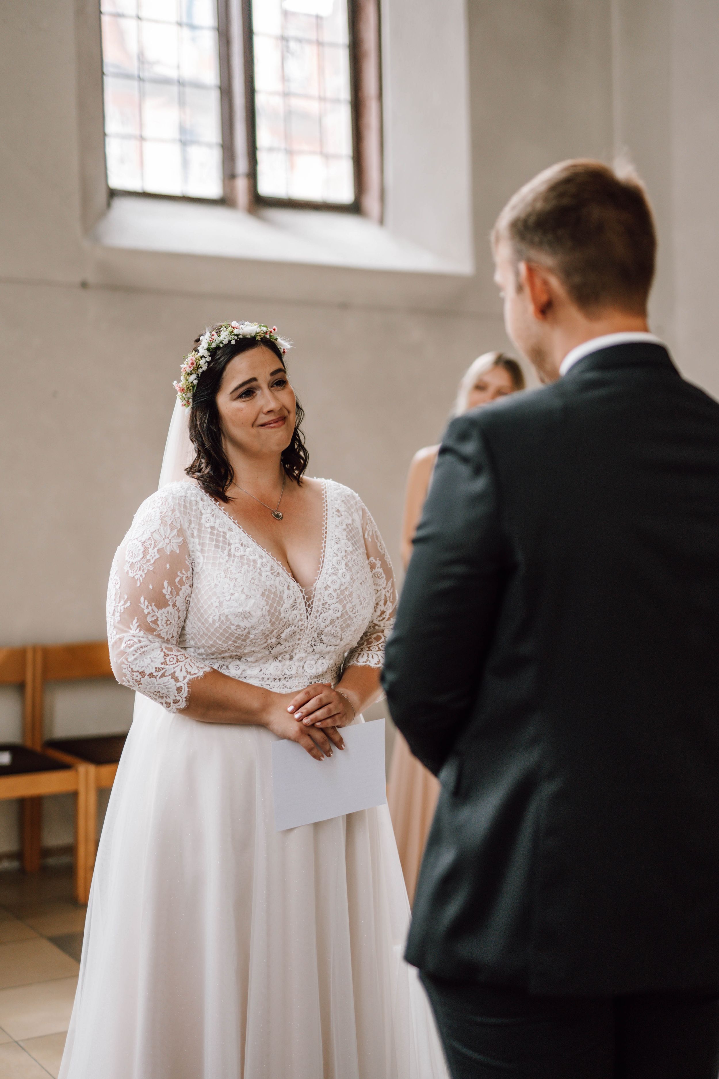 Couple exchanges vows in a bright, minimalist church setting.