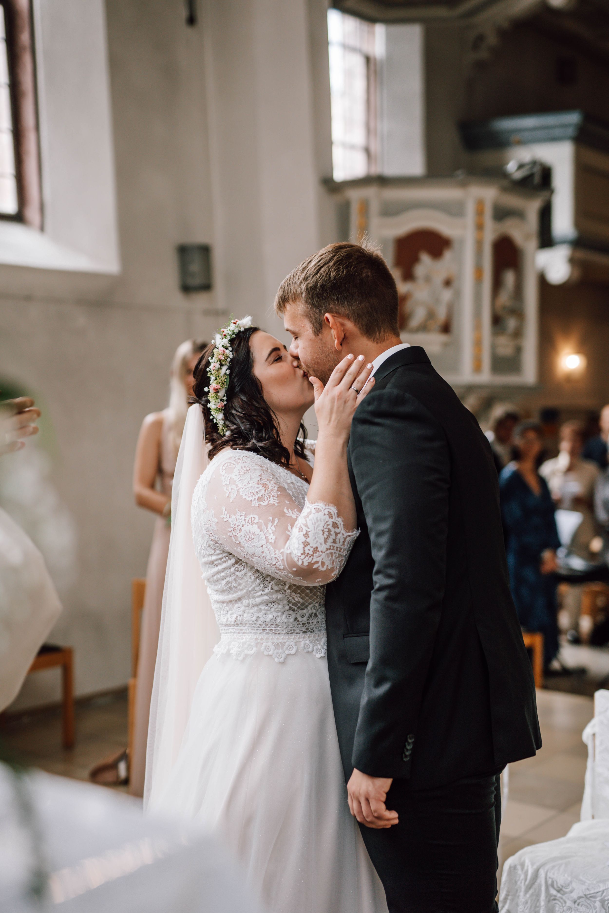 A romantic wedding ceremony kiss captured in a beautiful church setting with ornate details.