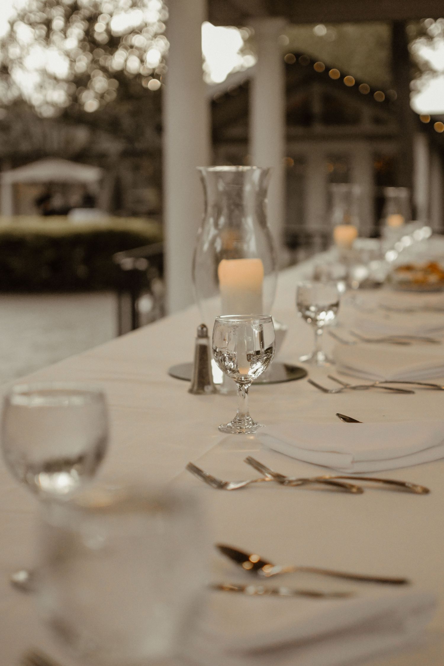 Elegant table setting with glassware and silverware arranged for a wedding reception.