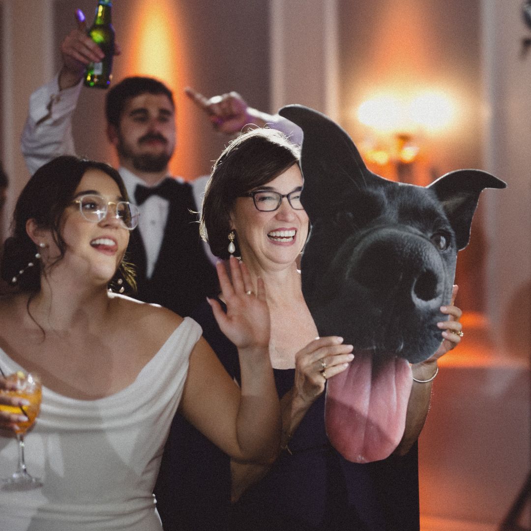 A playful moment at a wedding reception featuring a large dog's face and laughter.