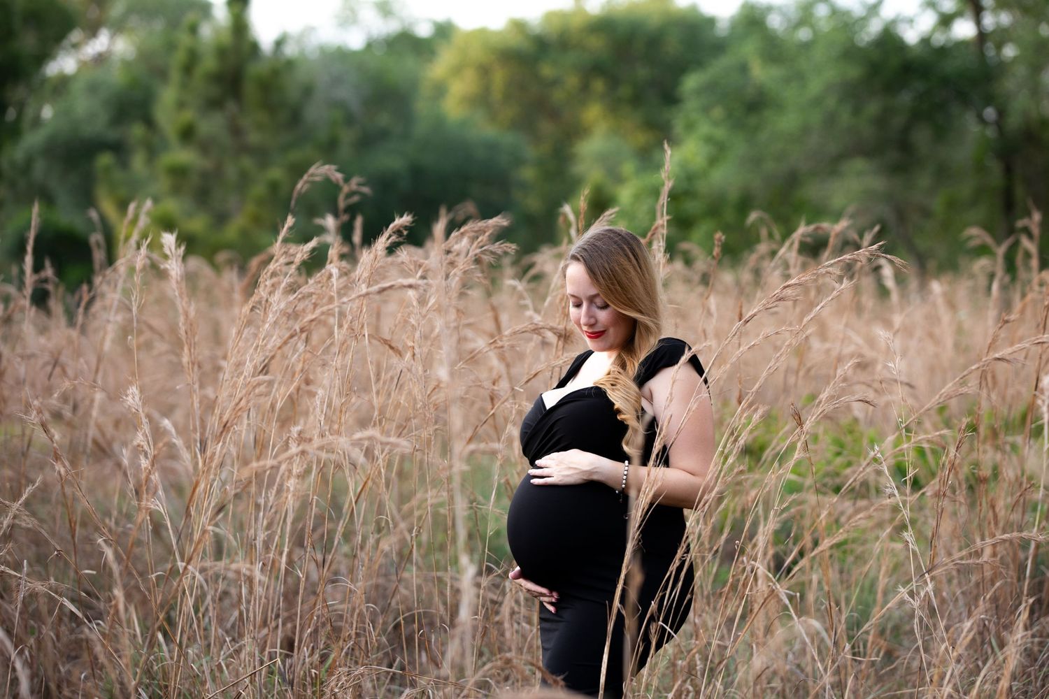 Professional photographer taking portraits in tall golden grass during golden hour.