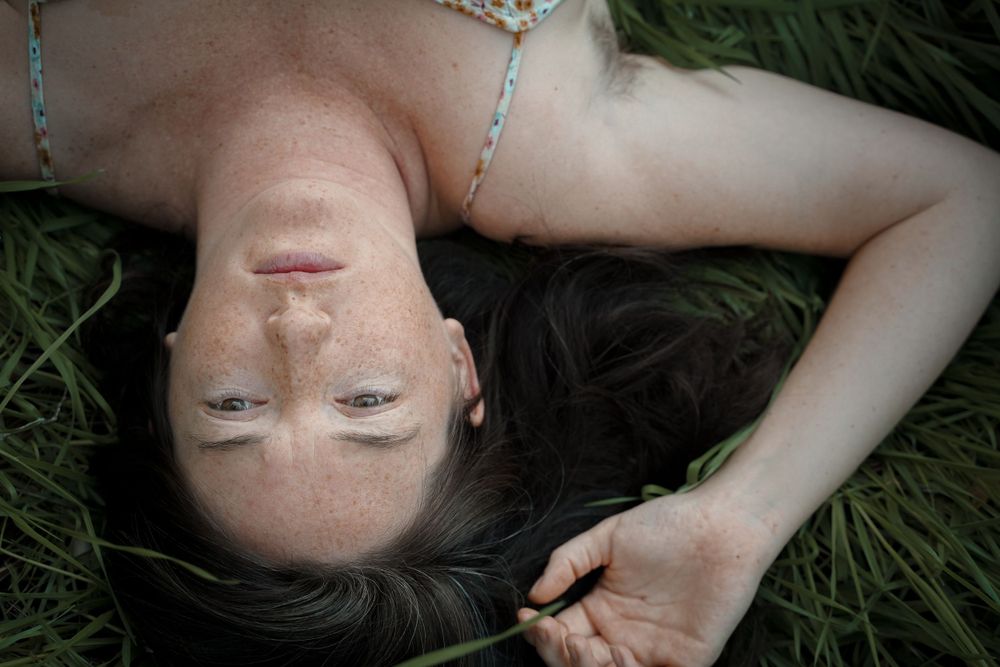 Close up portrait of person lying in grass with delicate jewelry.