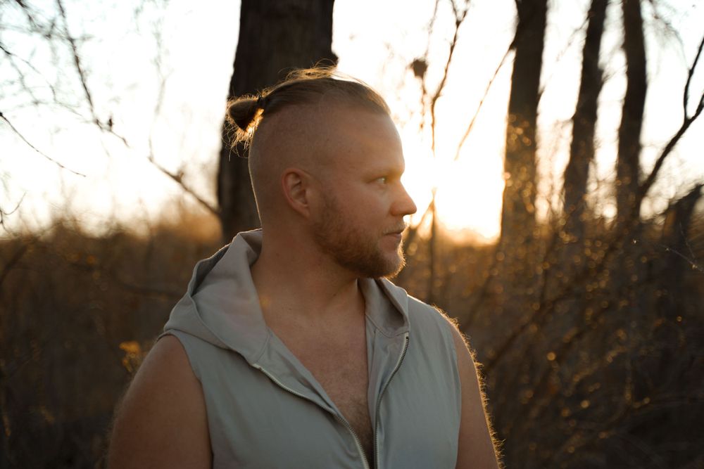 Profile shot of a person in sleeveless hoodie at sunset with golden backlighting.