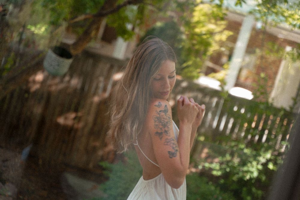 A dreamy portrait in a garden setting with soft sunlight filtering through trees.