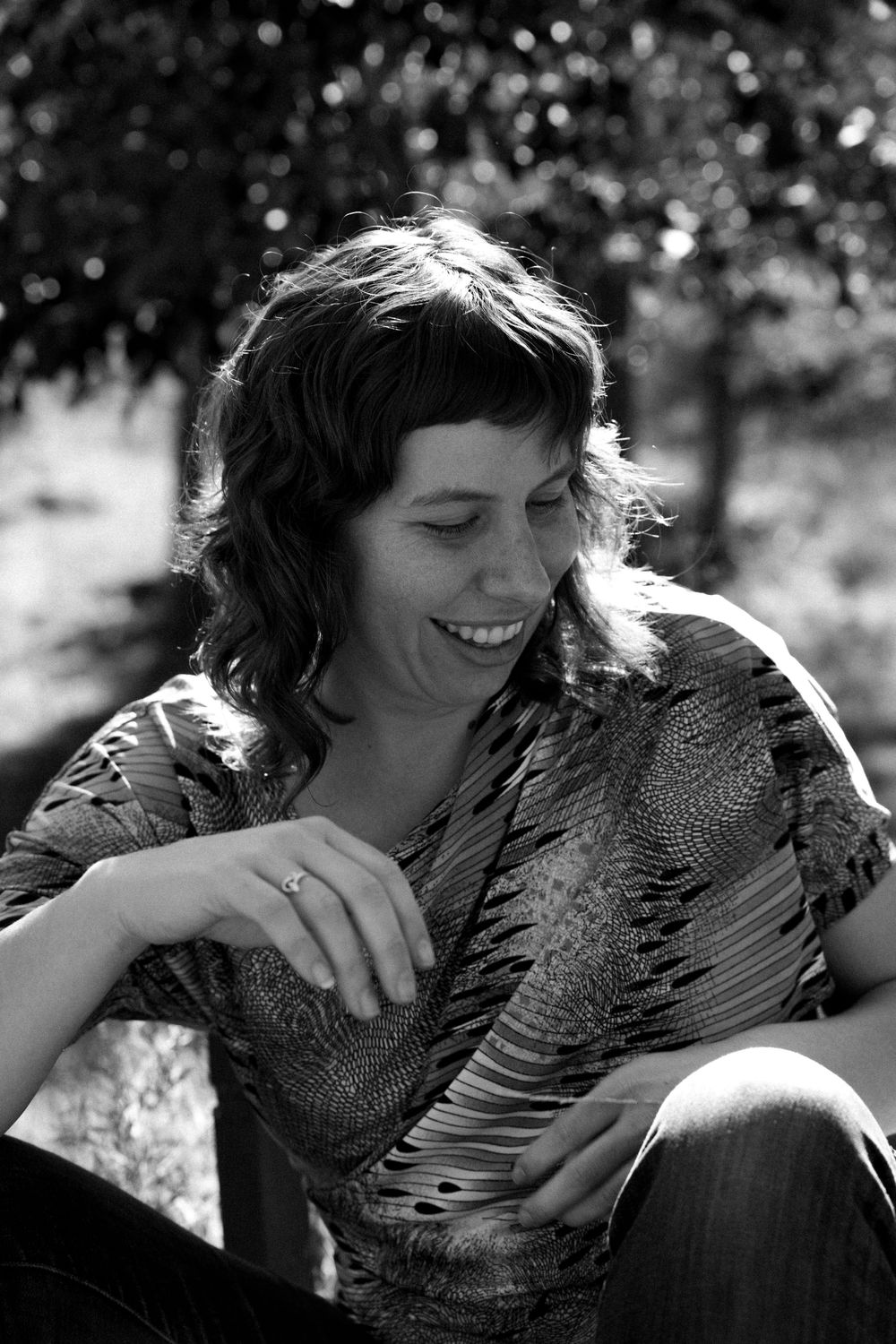 Candid black and white portrait showing joyful expression in dappled sunlight.