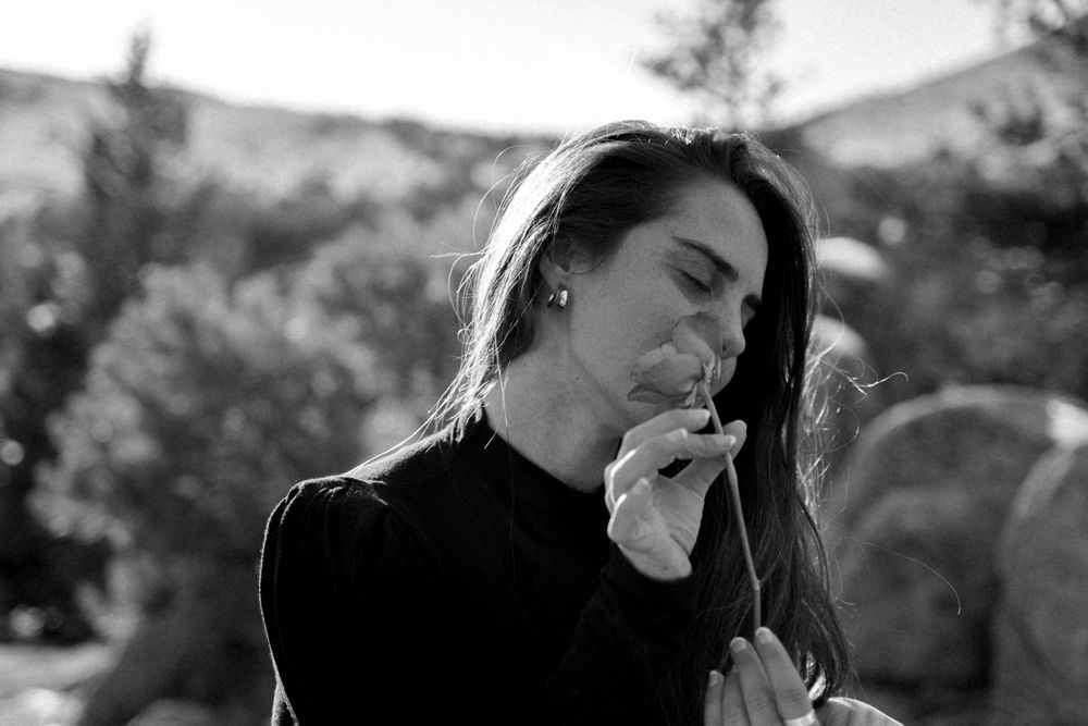 Monochrome portrait showing contemplative moment outdoors with mountains in background.