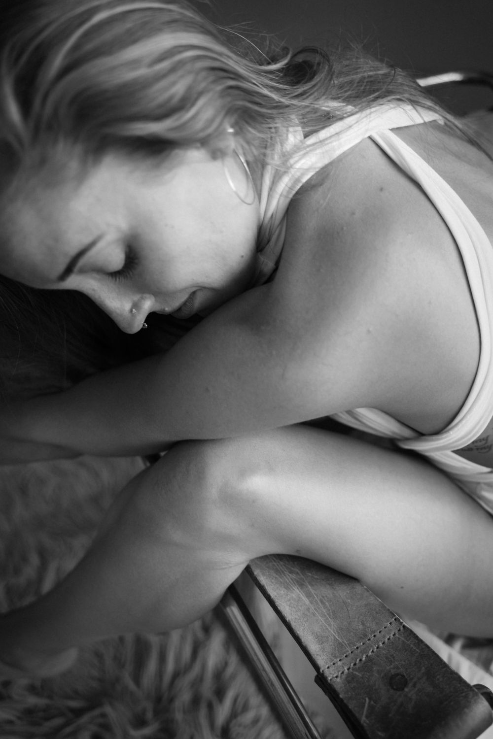 Artistic black and white photo of someone resting on textured bedding.