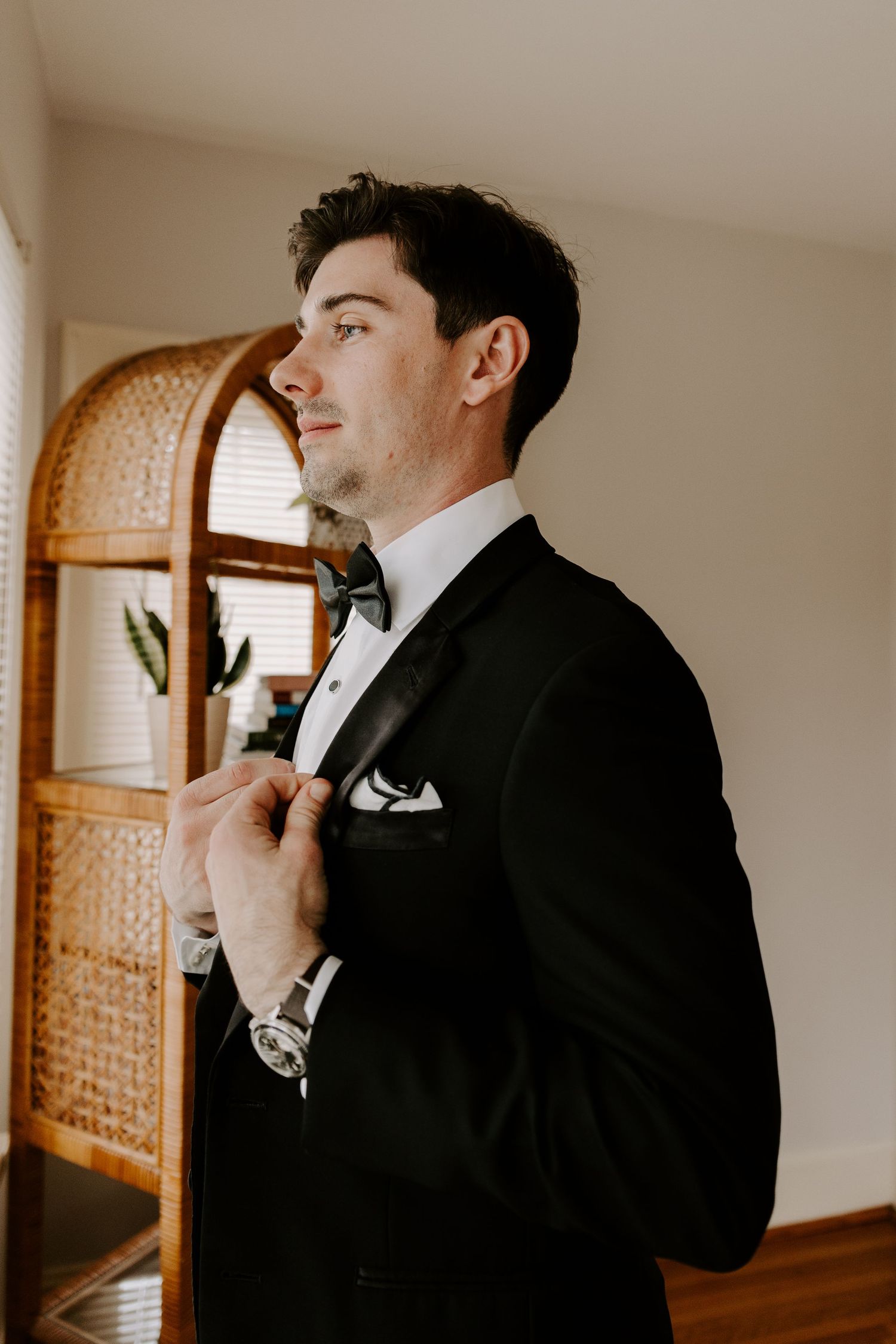 Close-up of formal attire being adjusted with ornate rattan furniture in background.