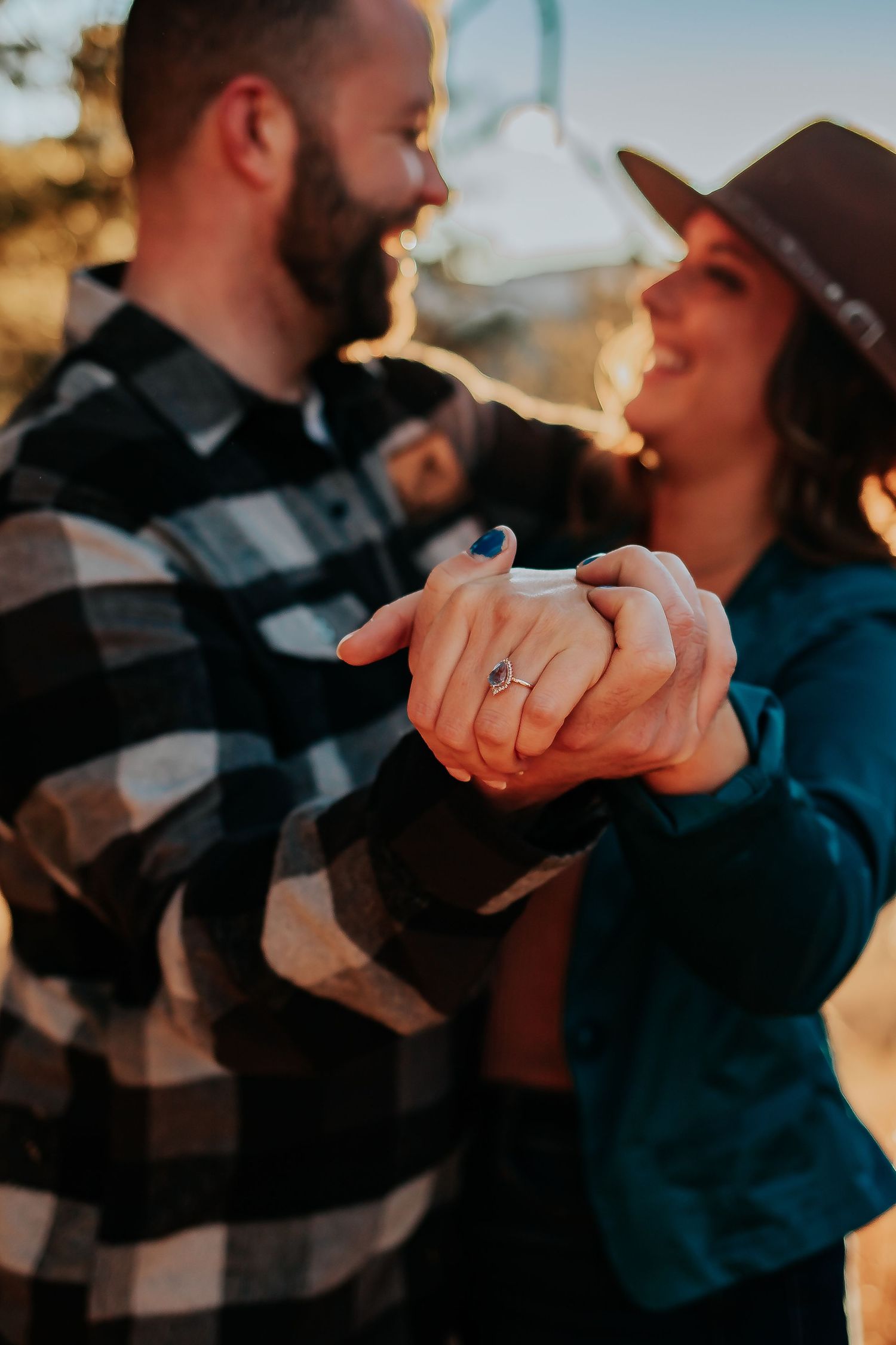 Couple in casual wear dancing together at sunset, showing off engagement ring. Denver engagement Photography.