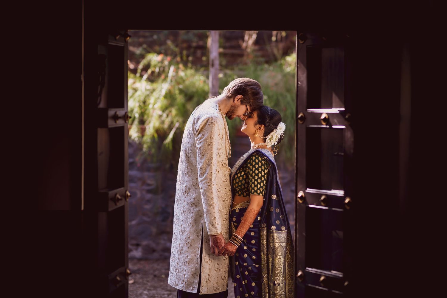 A romantic couple shares an intimate moment in traditional Indian wedding attire.