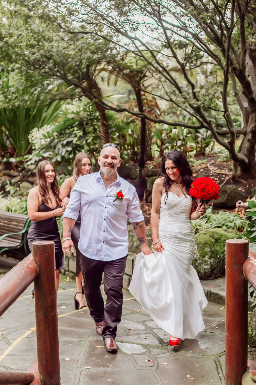 Garden pathway scene with wooden posts and people celebrating in white and red attire.