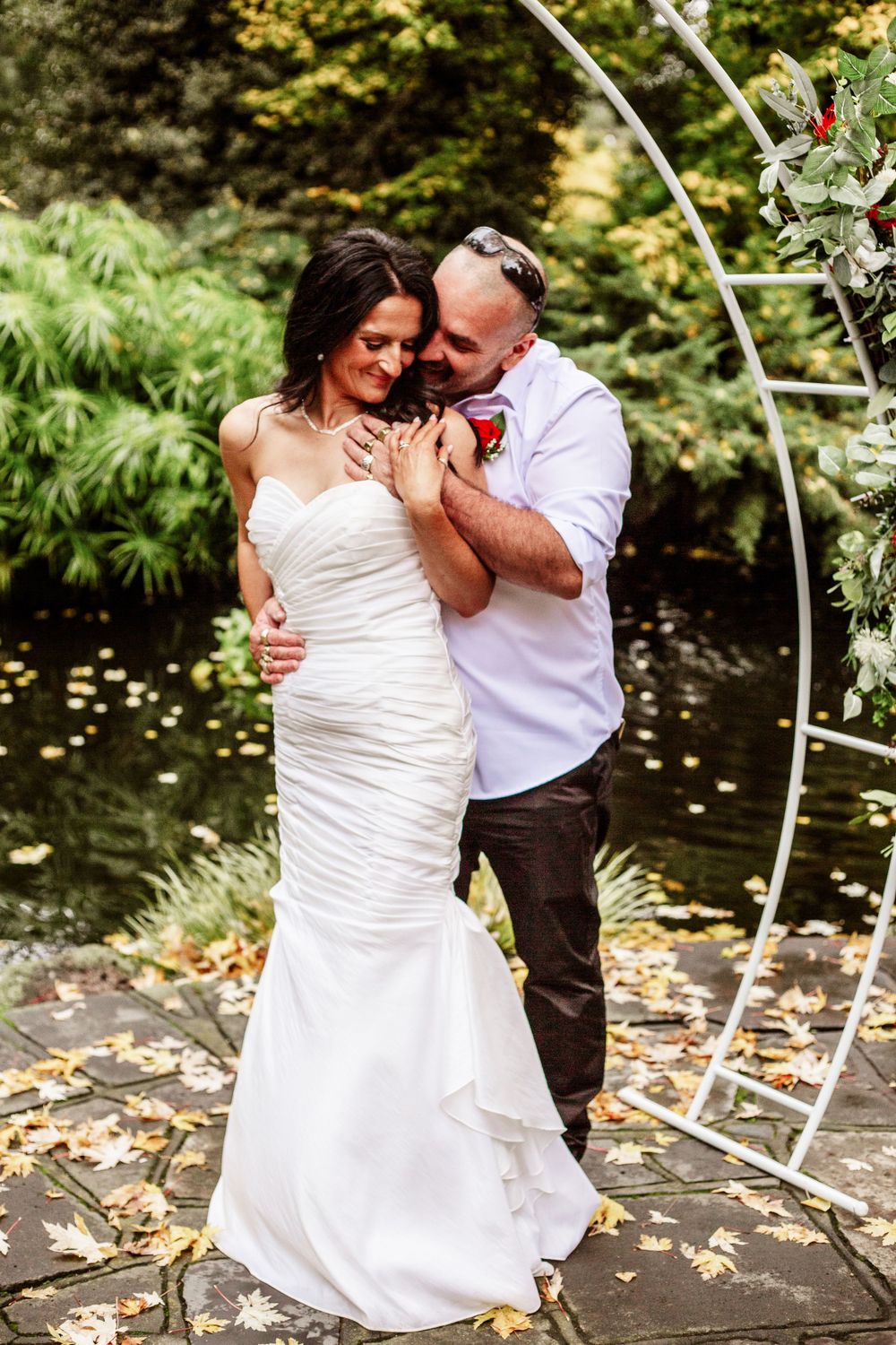 Romantic wedding couple shares intimate moments under a decorative arch in a garden setting.