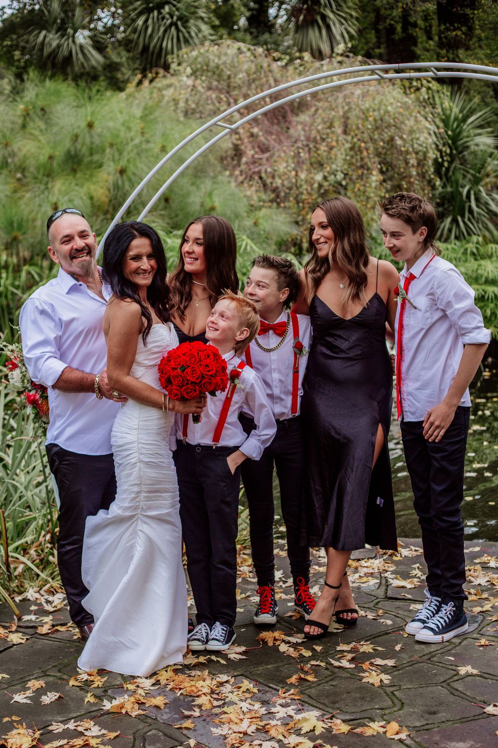 Wedding party gathers for casual group photos outdoors with children in matching outfits.