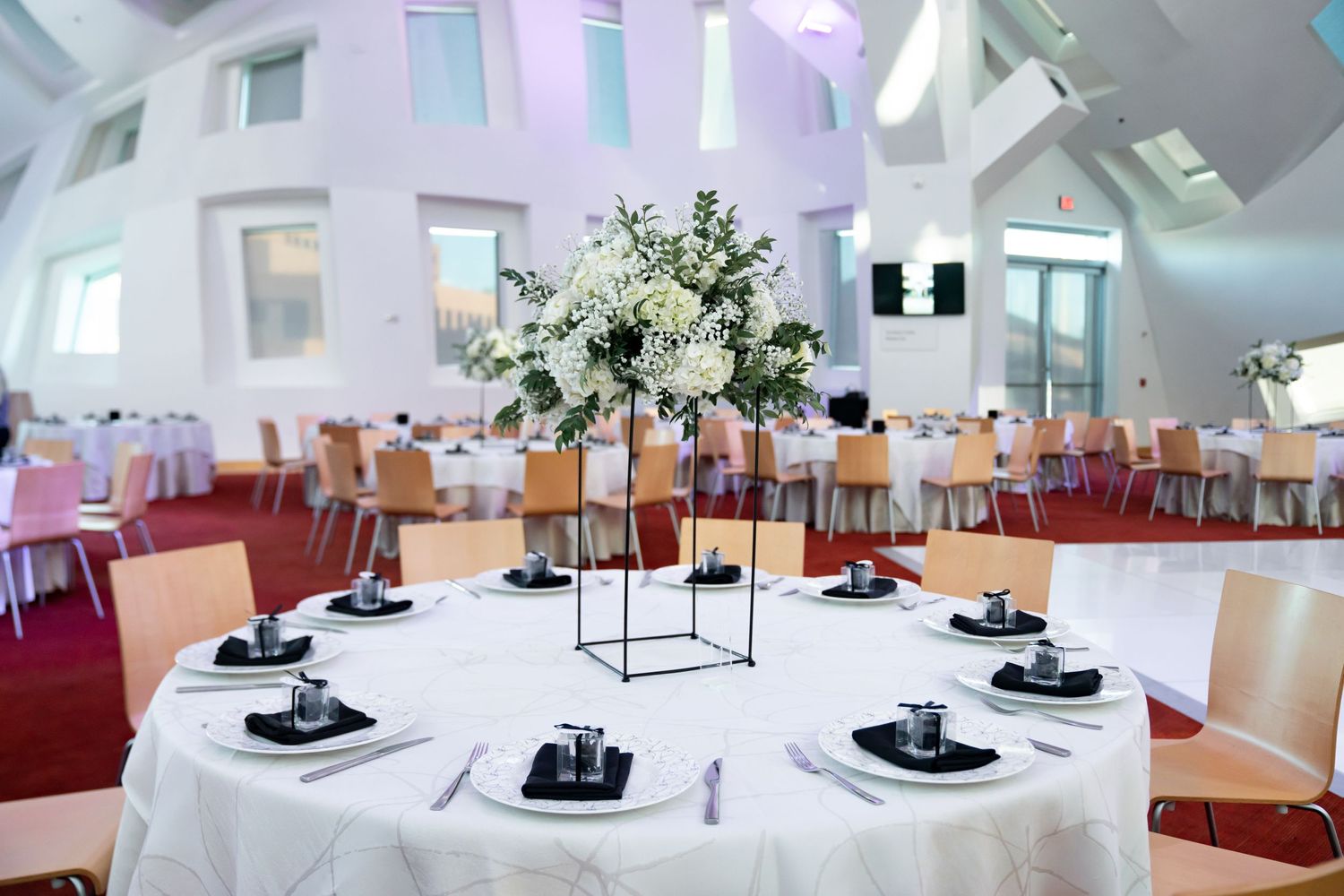 Elegant wedding reception setup with white floral centerpiece and modern geometric architectural details.