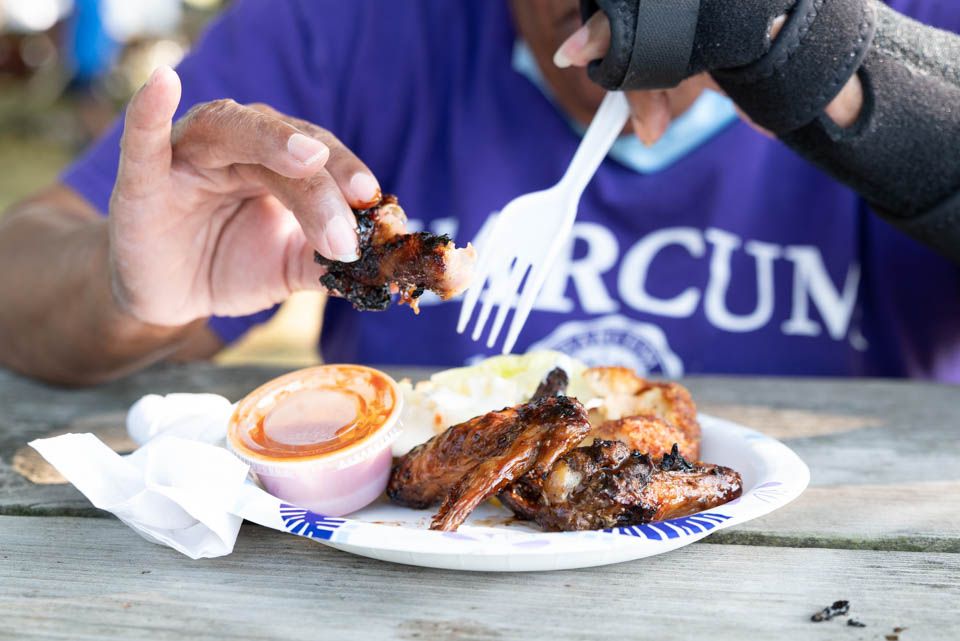 Pixs By Tina captures a close-up shots of hands serving and cutting into various grilled or smoked meat dishes on white plates.