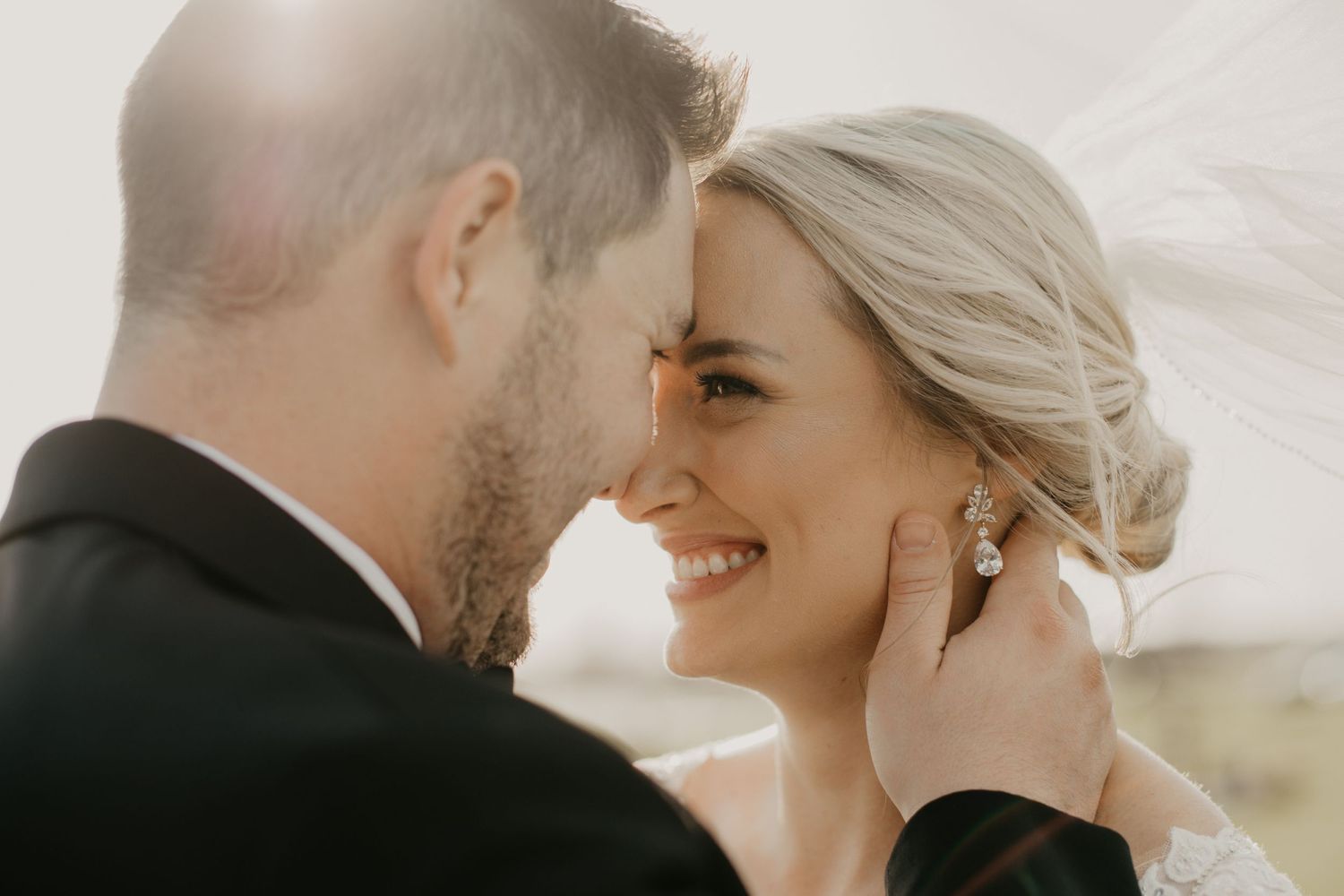 Intimate wedding portrait of couple sharing tender moment with flowing veil.